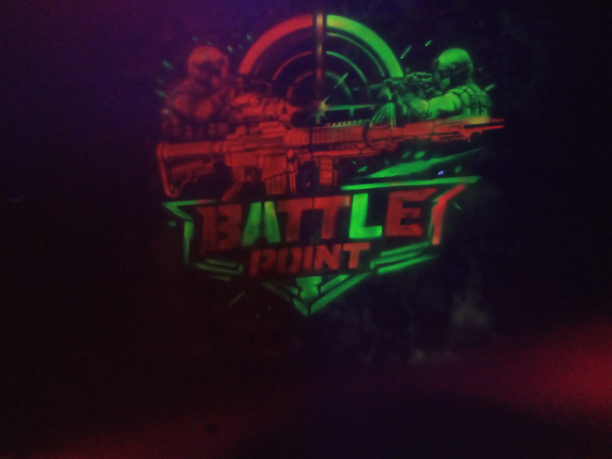 Logo Battle Point świecące w ciemności w kolorach zielonym i czerwonym – neonowa grafika na ścianie areny